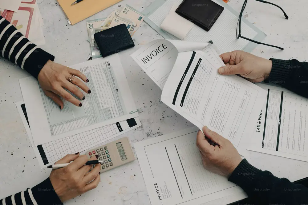 Two people going through invoices and forms with a calculator