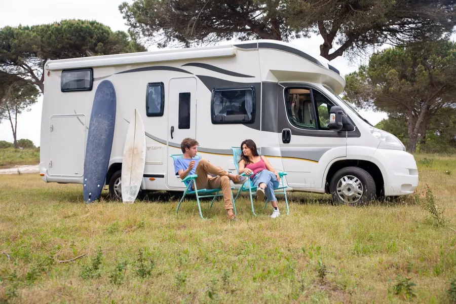 A couple relaxing in camping chairs beside their RV