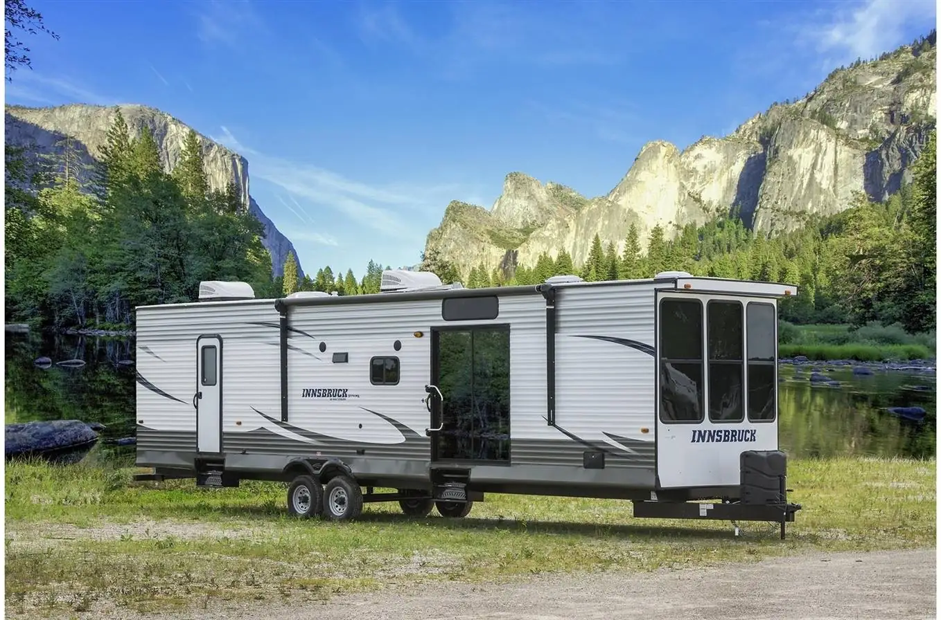 A destination trailer parked in a green valley below granite cliffs