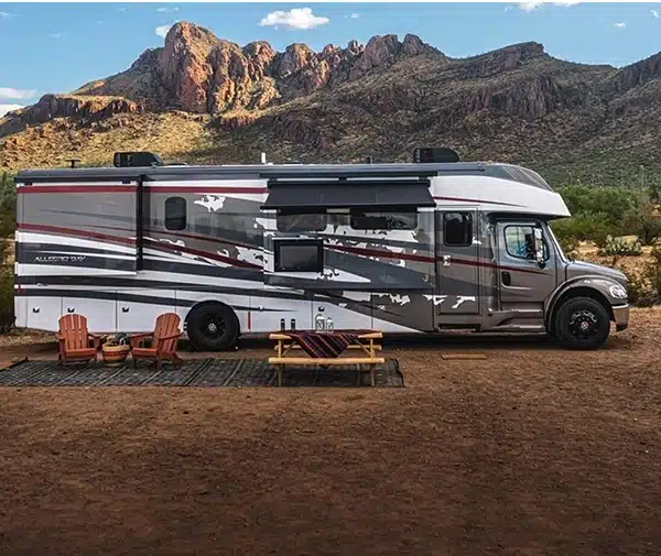 Motorhome at a desert campsite with chairs and a picnic table