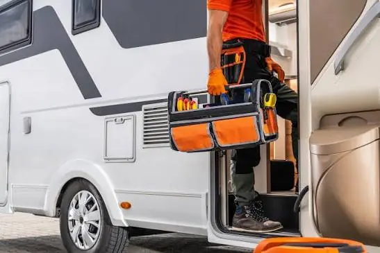 Technician carrying a tool bag into an RV
